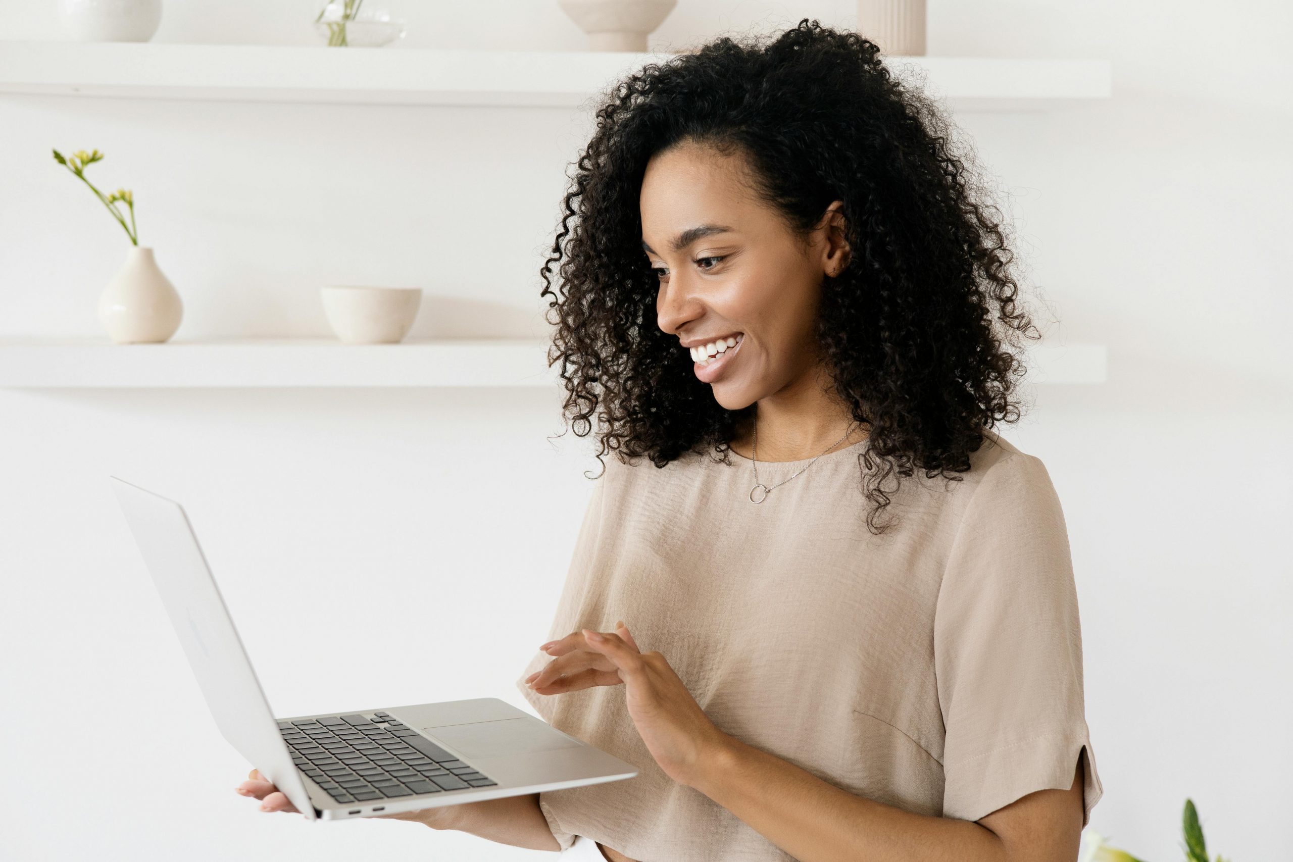 smiling woman holding a laptop in one hand and using the touchpad with the other