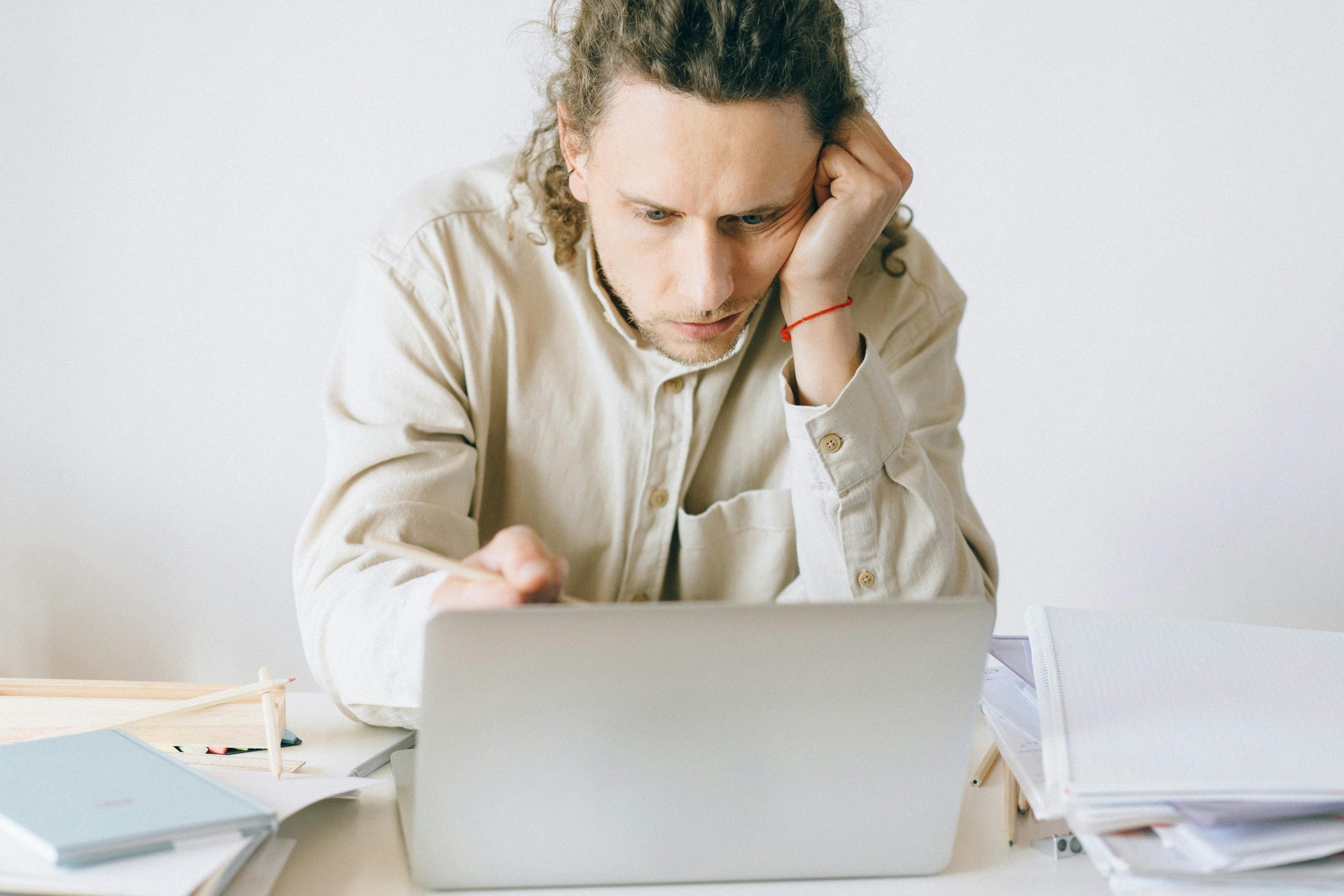 man working on a laptop, leaning his face against his hand