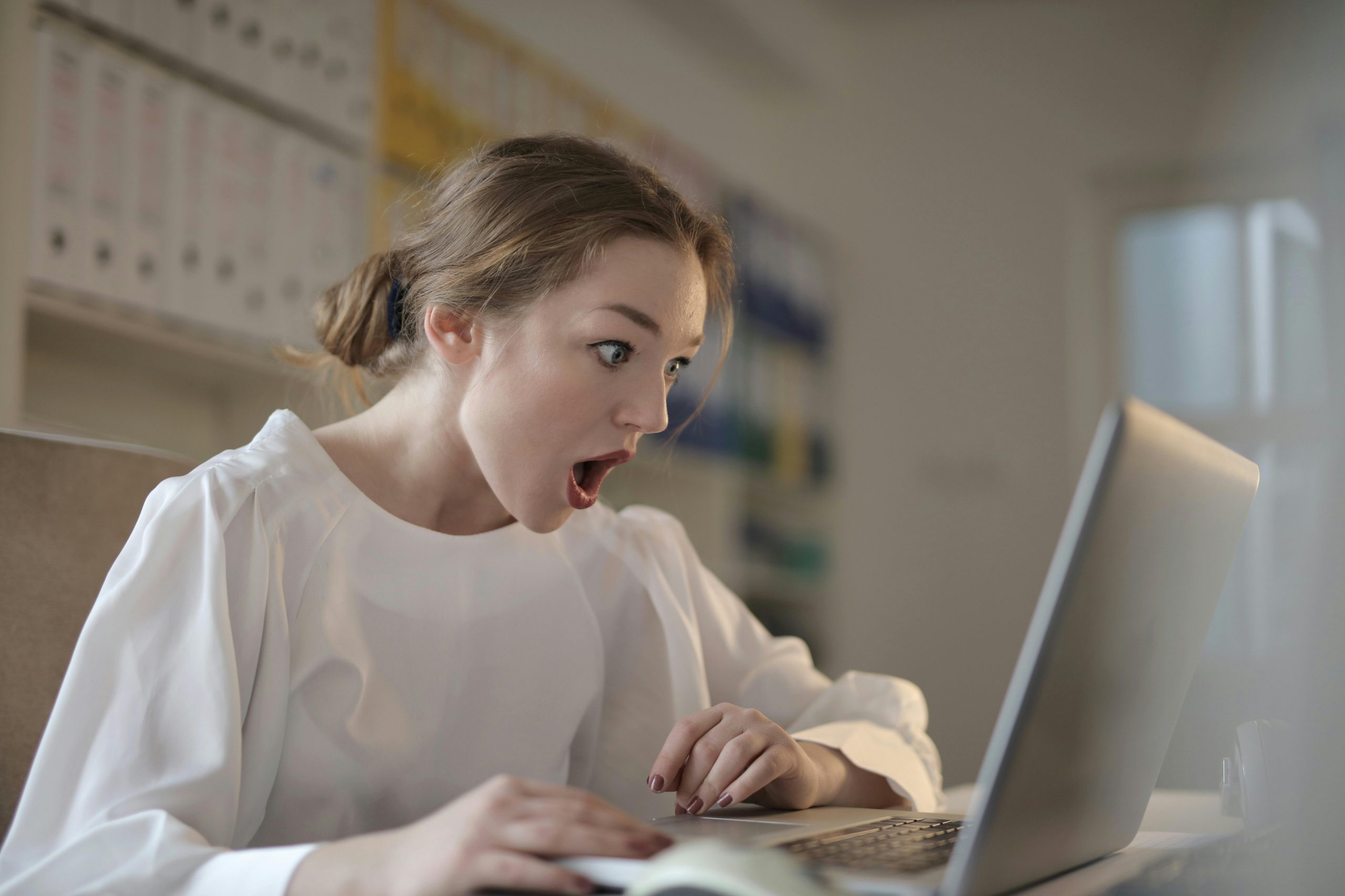 woman gaping at her laptop screen, appearing frustrated