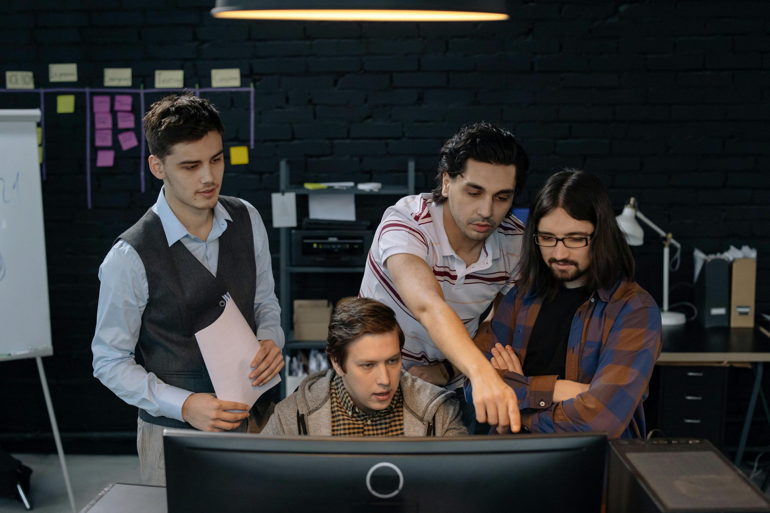 four employees gathered around a desktop computer