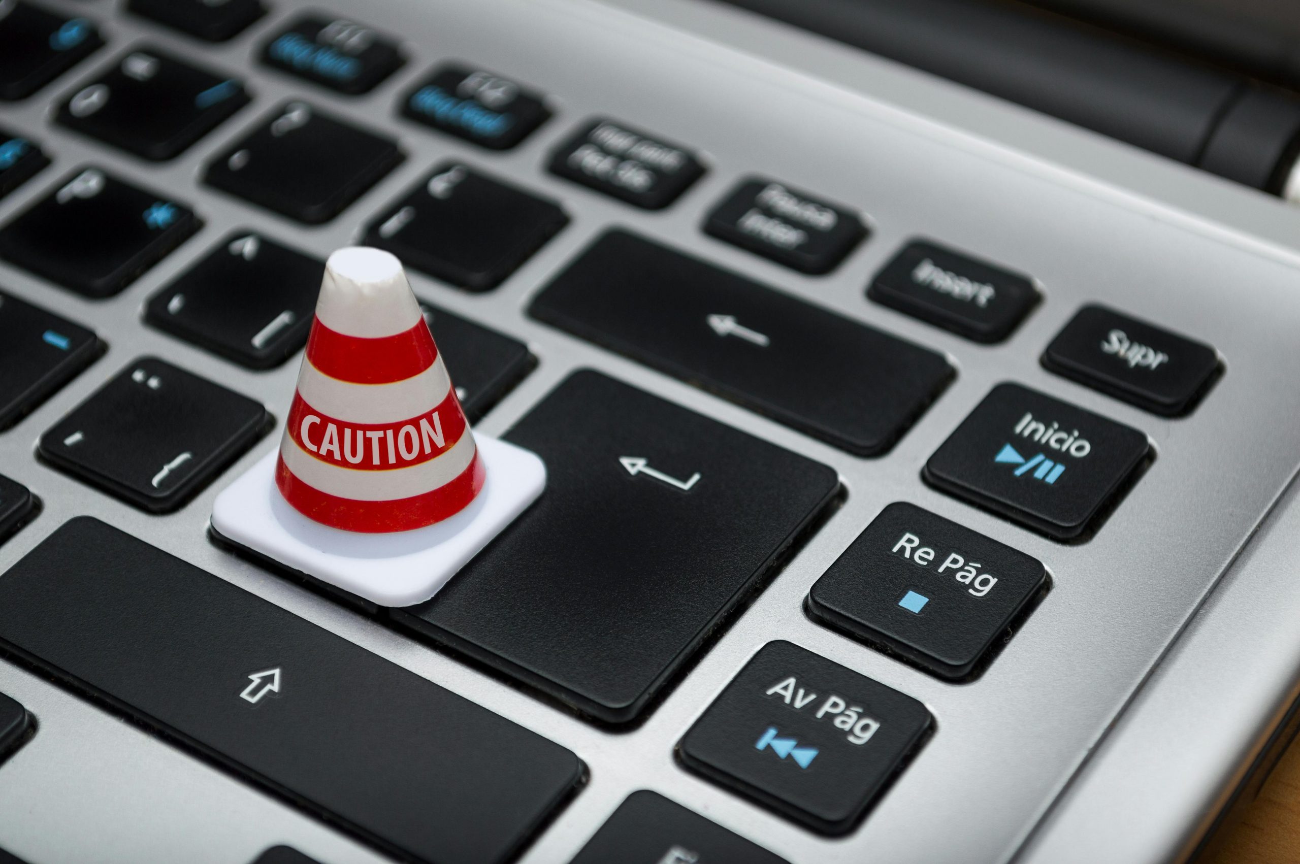 miniature traffic cone with a "caution" label on a laptop keyboard