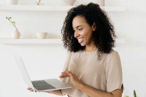 smiling woman holding a laptop in one hand and using the touchpad with the other
