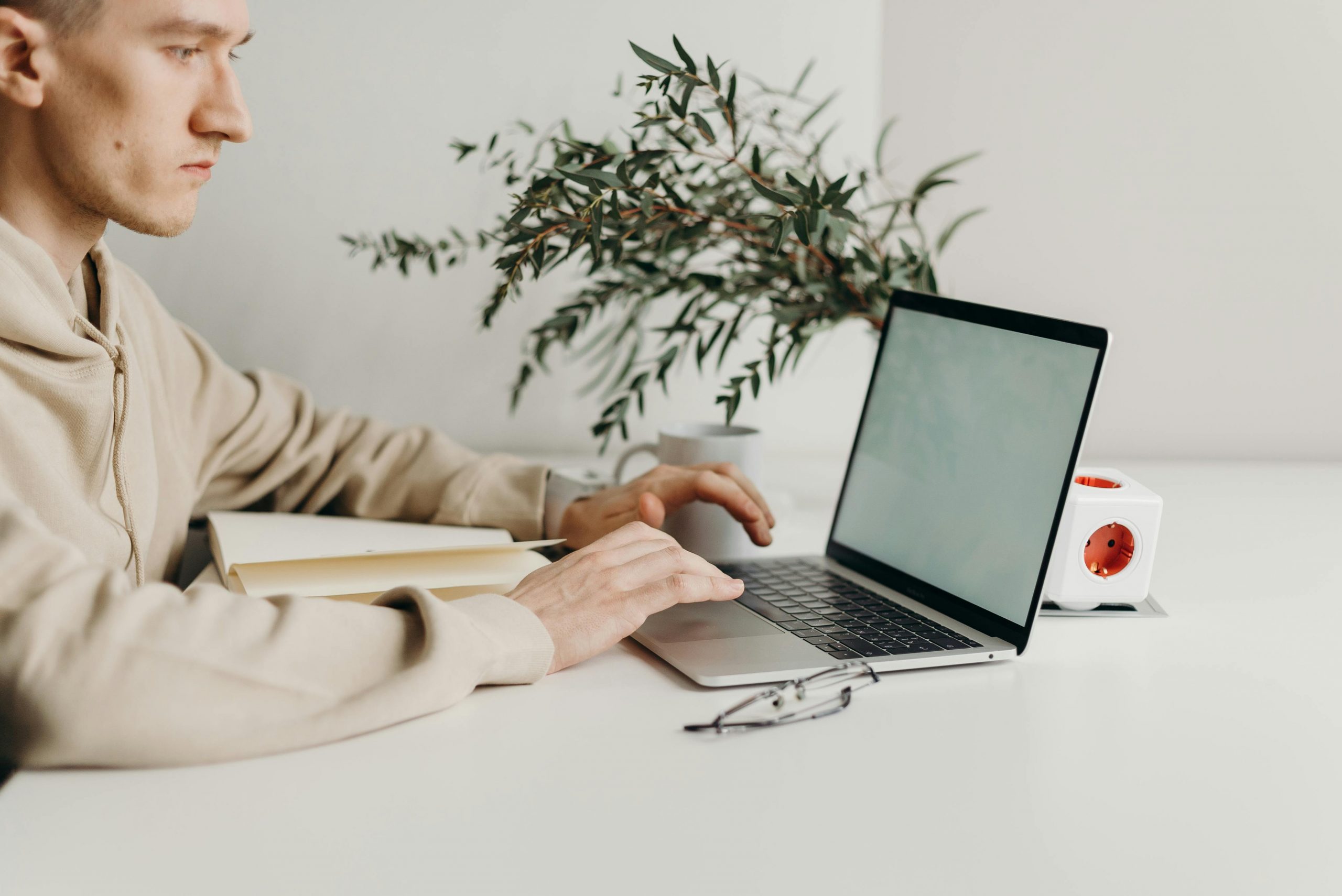 man wearing a hoodie typing on a laptop