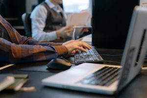 two people working at desks, typing on desktop keyboards
