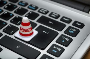 miniature traffic cone with a "caution" label on a laptop keyboard